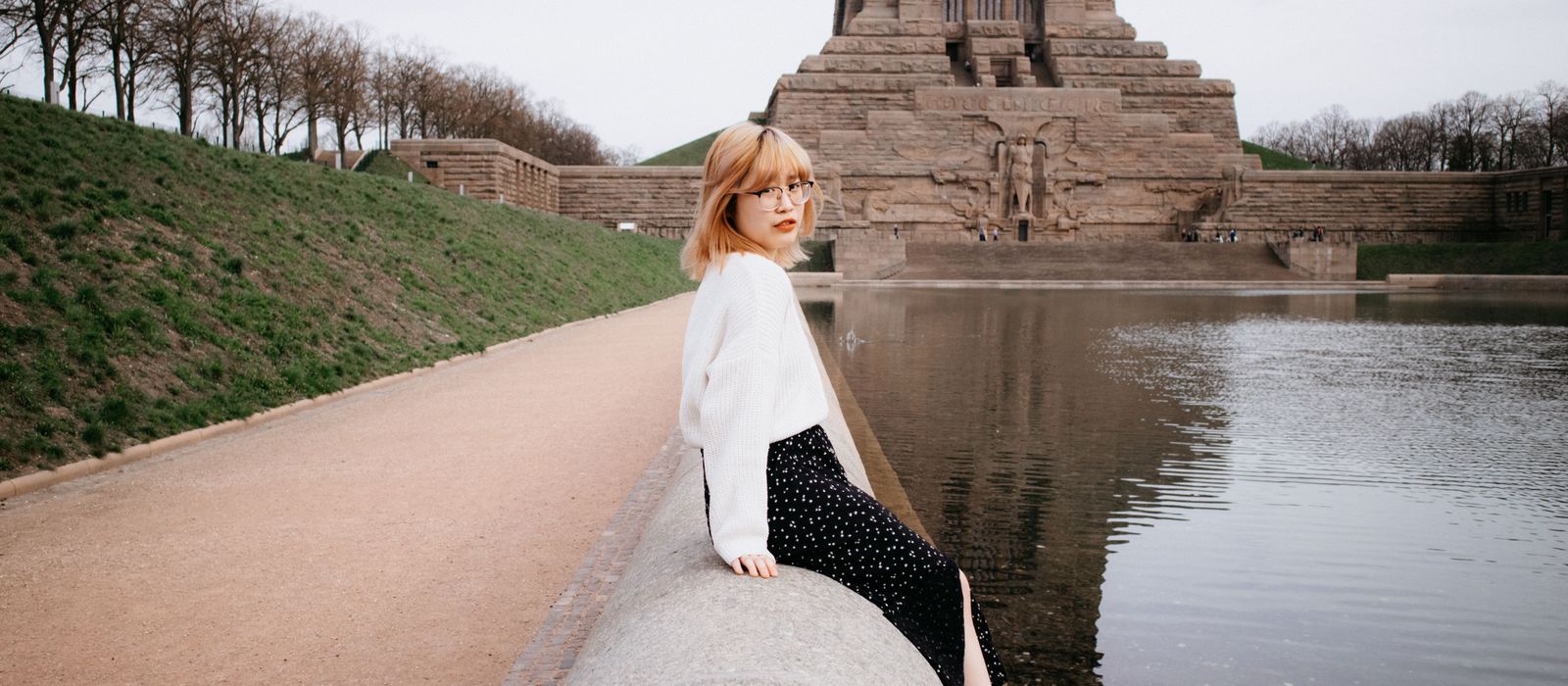 A young woman sits by the Völkerschlachtdenkmal monument in Leipzig, Germany.