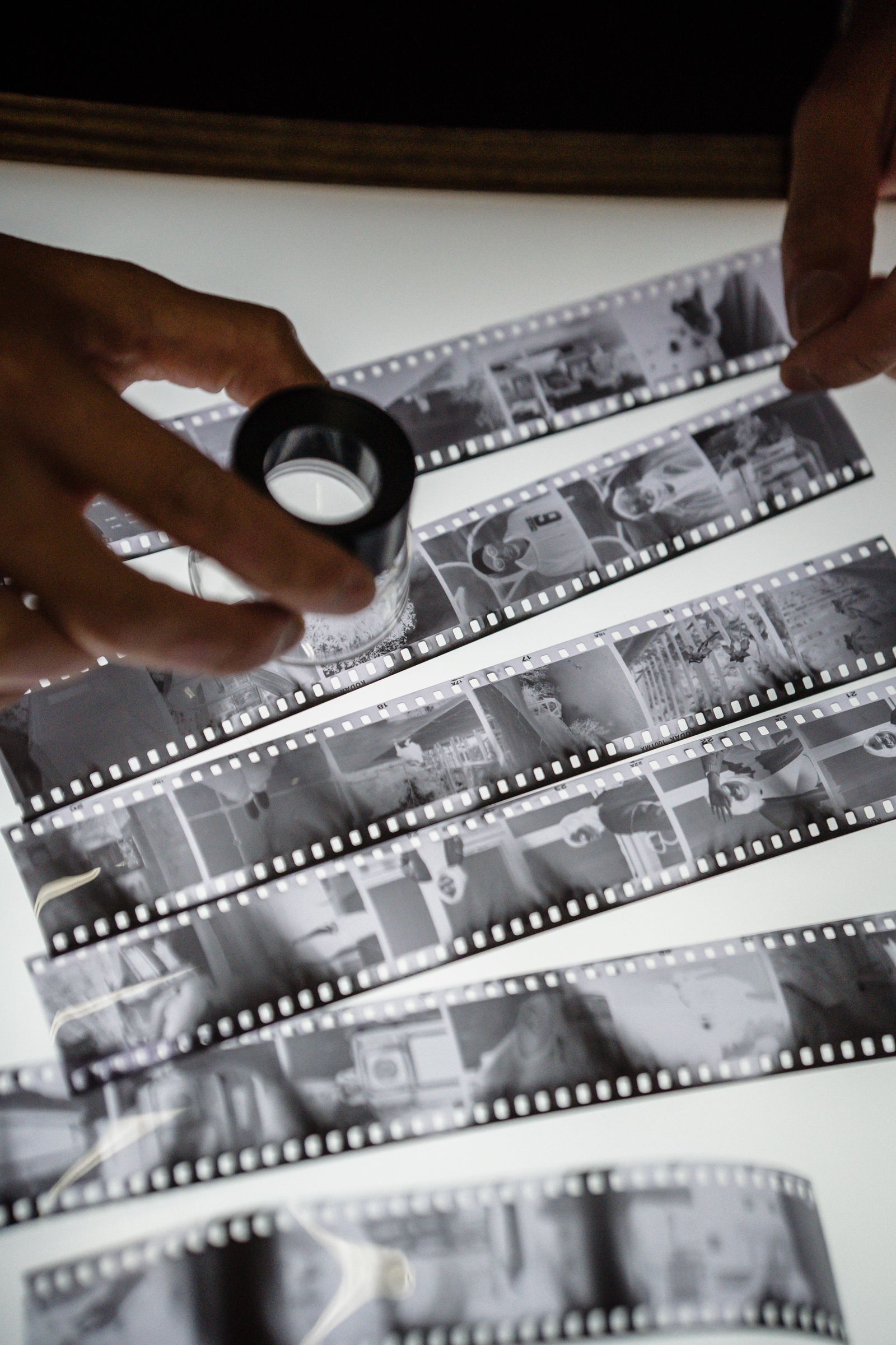 Person checking a film strip against a bright light source