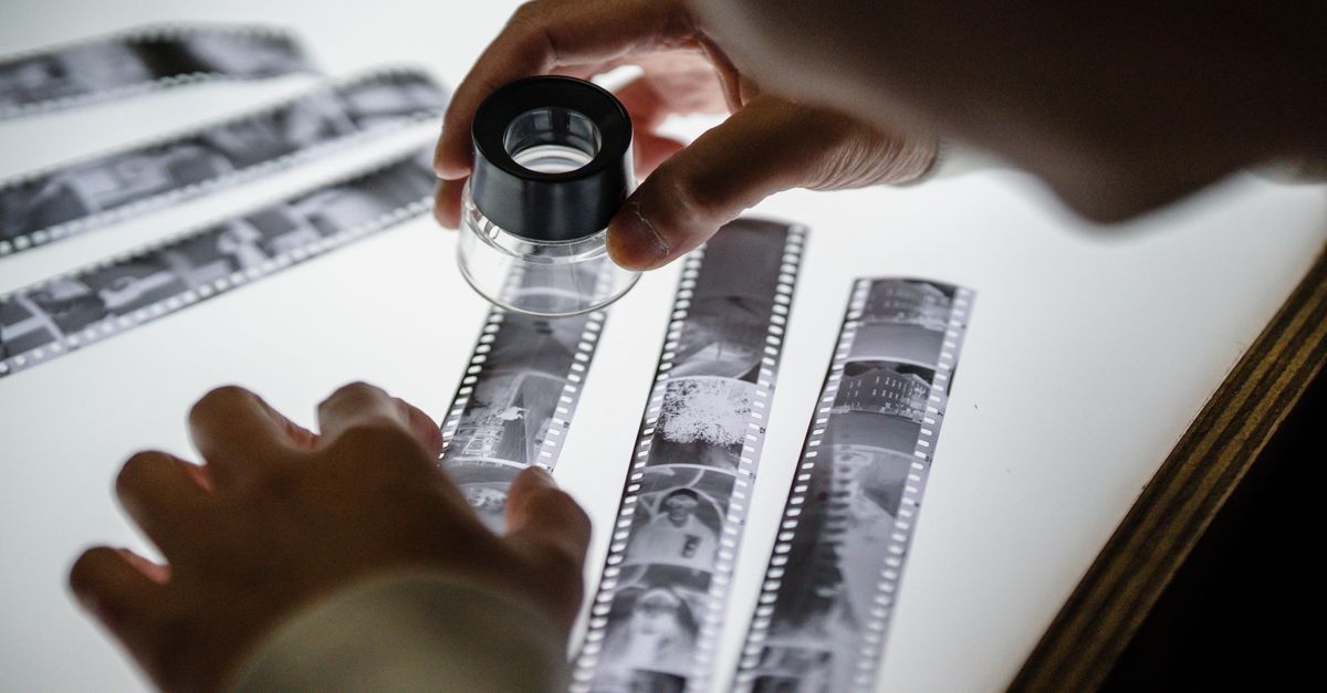 hands developing black and white film photographs in a darkroom