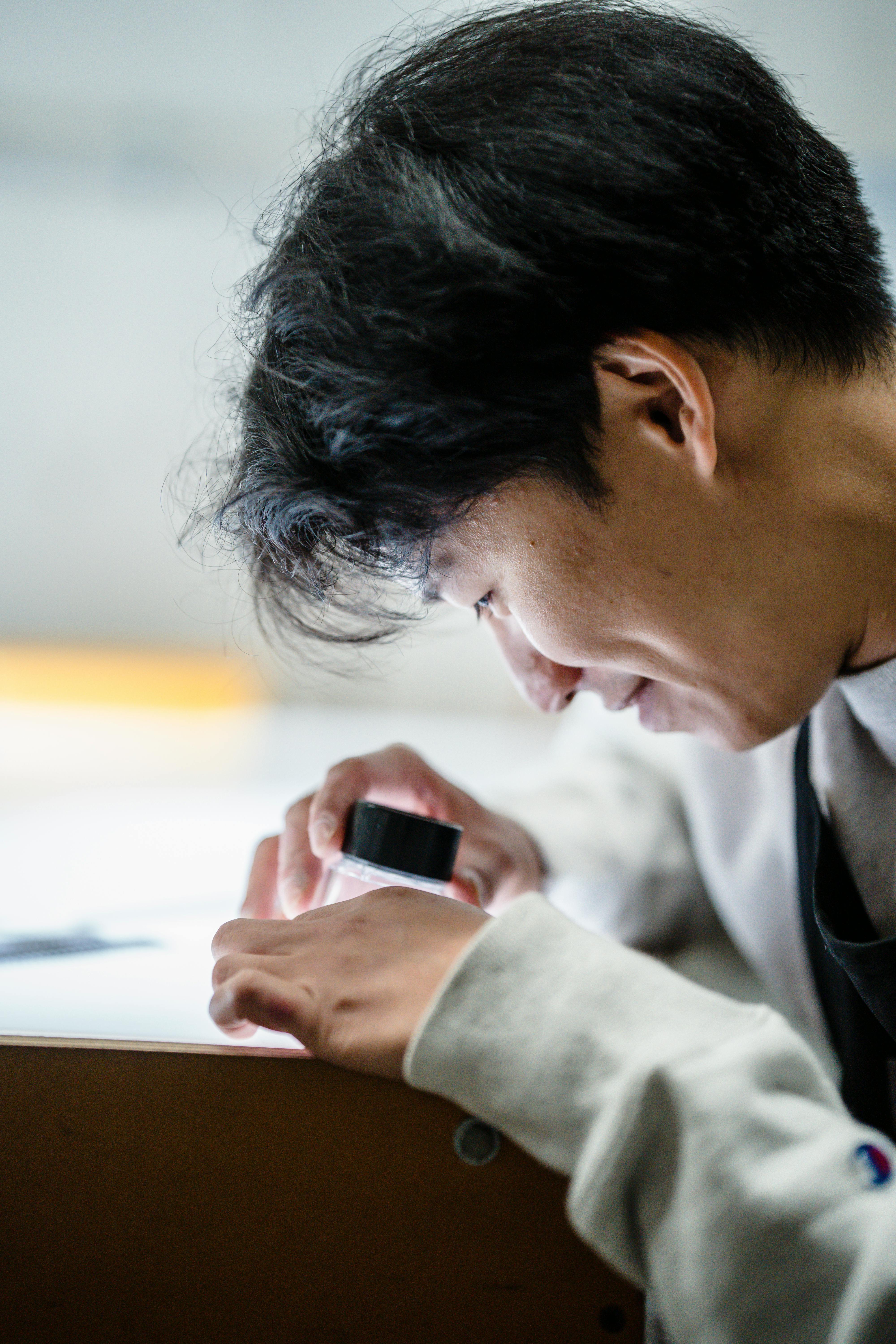 A person carefully examining a mushroom with a magnifying glass in a lush Auckland park.