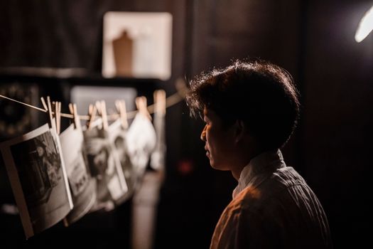 A contemplative moment in a darkroom with photographs hanging to dry, capturing the essence of traditional photography.