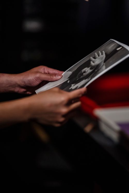 Free Close-up of hands holding a black and white photograph in a darkroom setting. Stock Photo