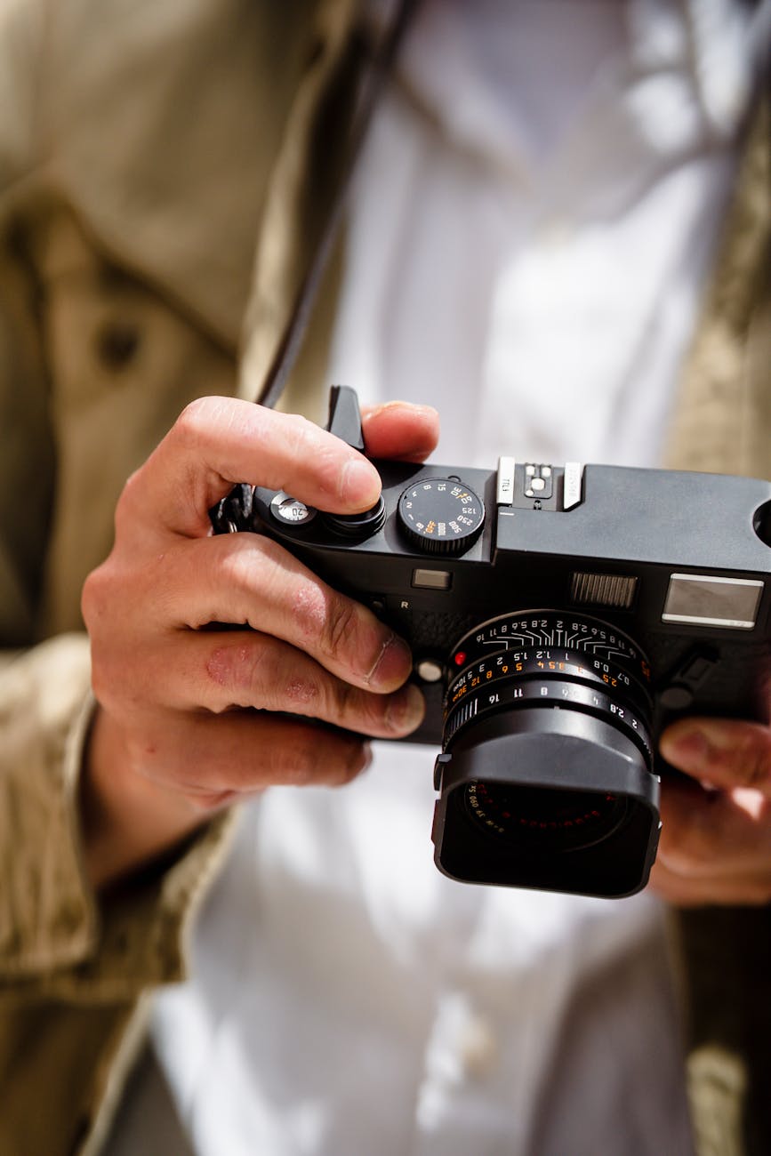 Detailed shot of hands adjusting settings on a classic camera with blurred background.