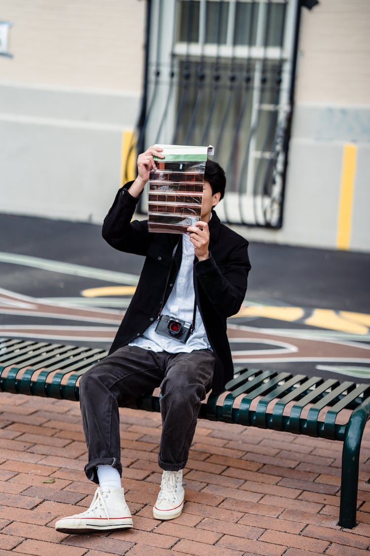 Man Sitting On Bench Looking At Roll Of Film