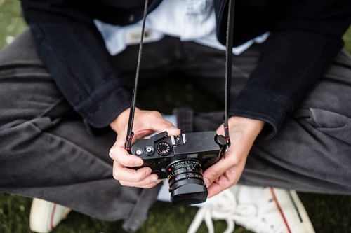 Free A person outdoors holding a camera on their lap, dressed casually. Stock Photo