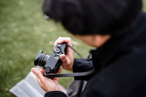 Free Close-up of a person adjusting a camera outdoors with a blurred background. Stock Photo