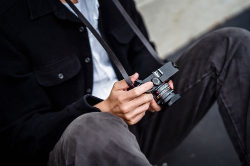 Free Close-up of an individual sitting and holding a mirrorless camera. Stock Photo