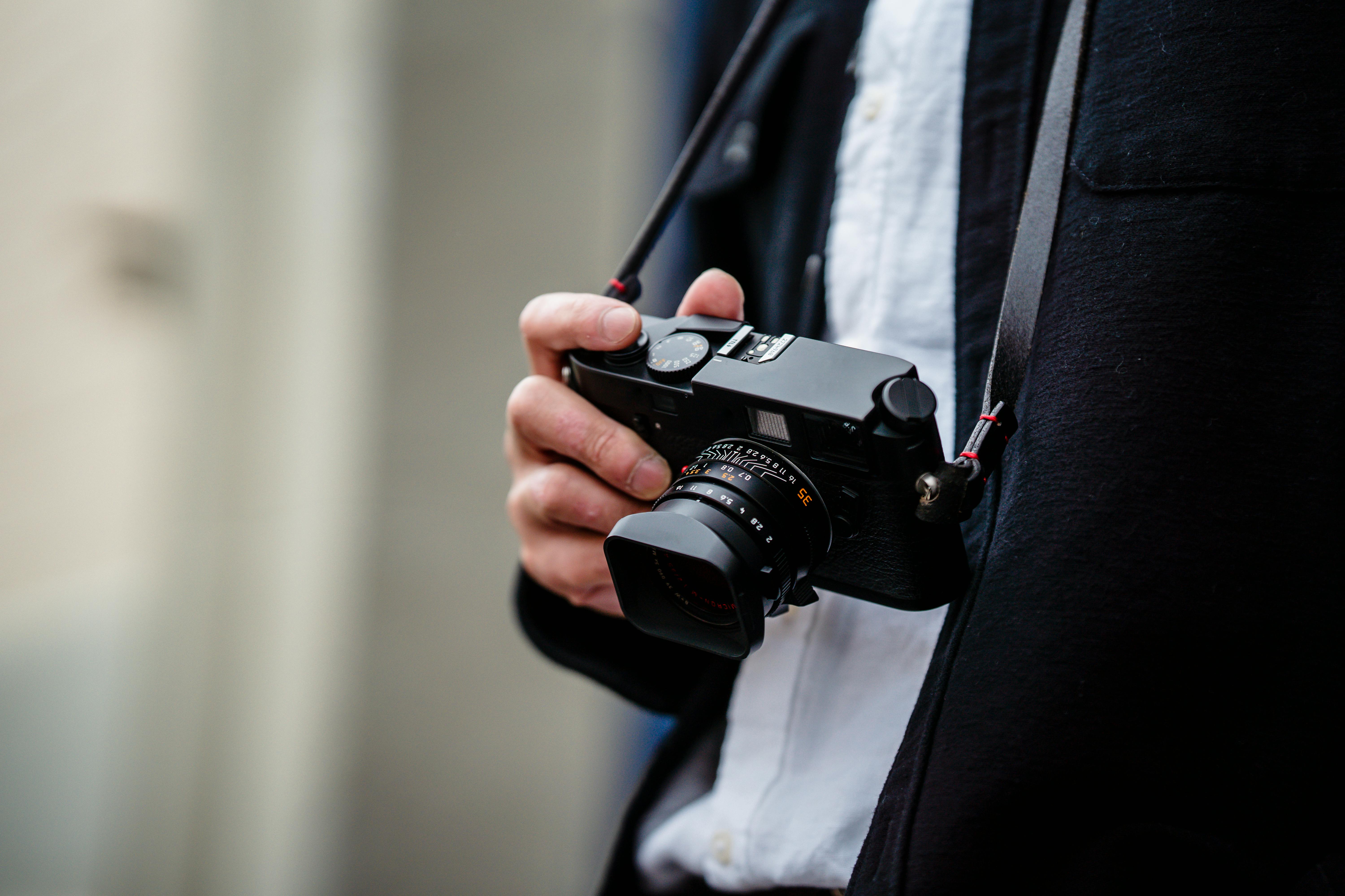 a person holding a black camera with strap