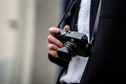 A Person Holding a Black Camera with Strap