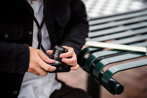 Close-up of Man Holding a Camera and Adjusting the Lens 