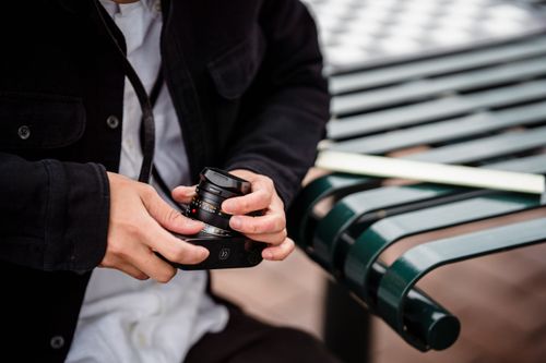 Free Photographer adjusting a camera lens outdoors on a bench. Stock Photo