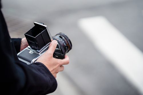 Free A close-up shot of hands holding a classic Hasselblad camera outdoors, perfect for photography enthusiasts. Stock Photo