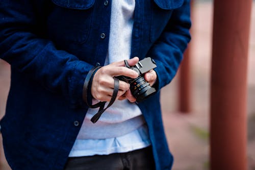 A Person in Blue Denim Jacket Holding a Black Dslr Camera