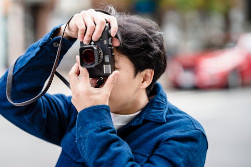 Shot of a Man in a Blue Shirt Taking Photograph with an Analogue Camera