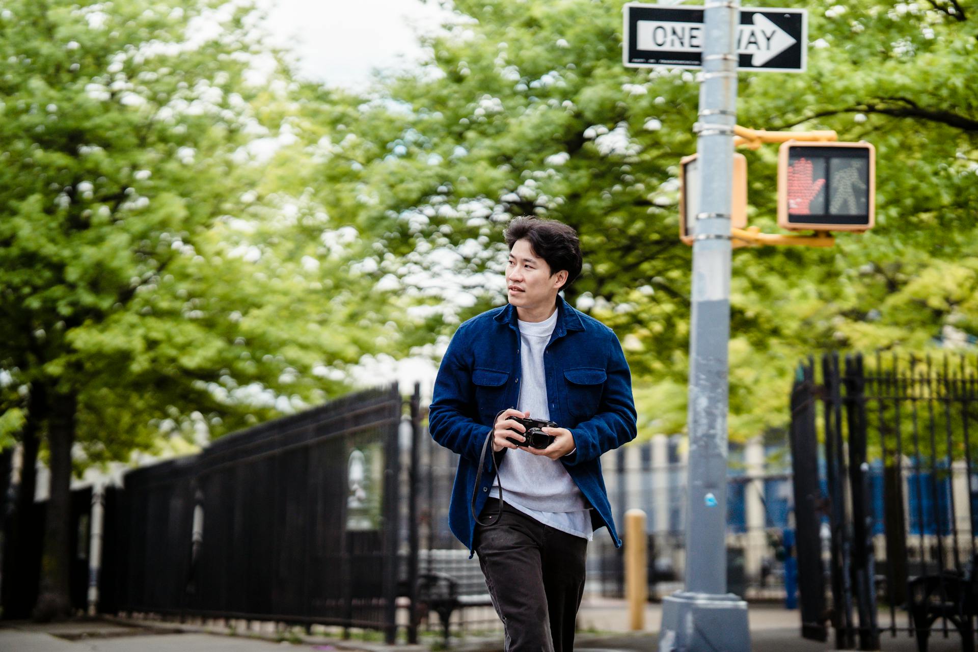 Young Man Crossing the Street With a SLR Camera in Hands