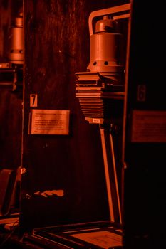 A vintage darkroom enlarger lit by red light used for developing photographs.