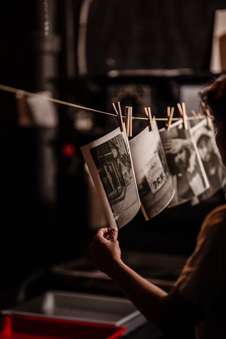 Close-up Of Man Handing Developed Pictures In A Darkroom 