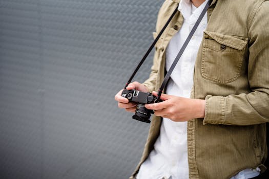 Person holding a vintage camera against a textured background, emphasizing style and photography.