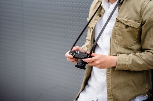 Free Person holding a vintage camera against a textured background, emphasizing style and photography. Stock Photo