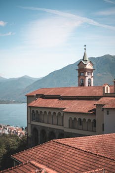 在晴朗的天空下，历史悠久的教堂以壮丽的山脉和湖泊为背景，风景如画