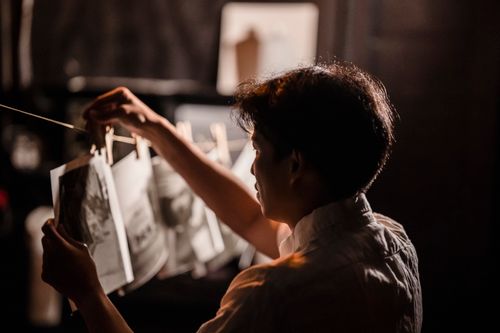 Free A photographer carefully examines and hangs prints in a darkroom setting. Stock Photo