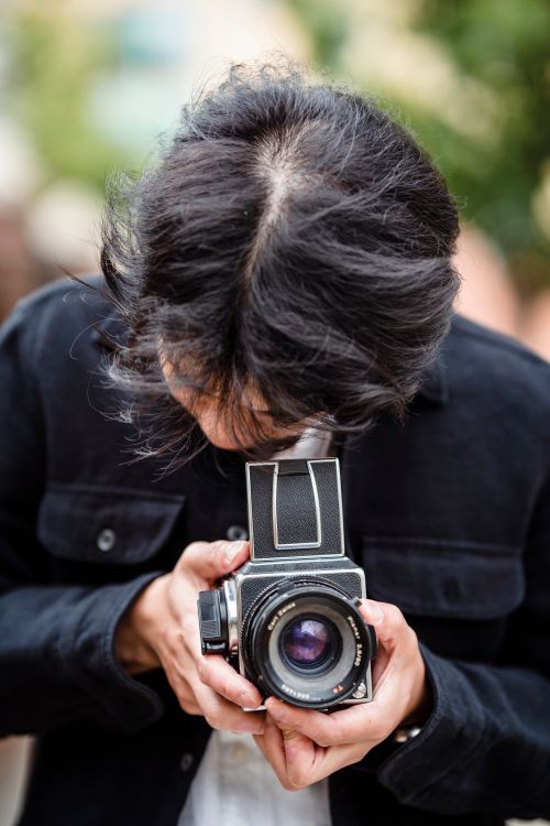 Free Man focuses on a vintage analogue camera during an outdoor photography session. Stock Photo
