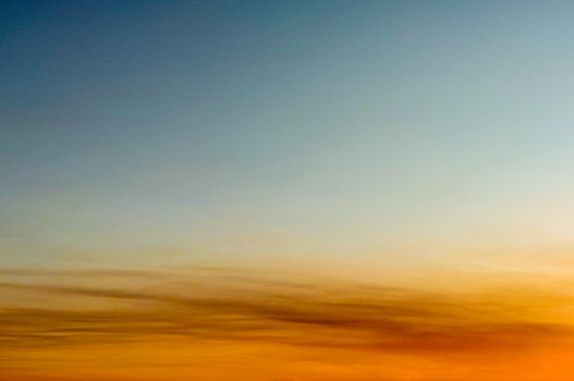 A tranquil sunset sky blending warm orange with cool blue hues, perfect for backgrounds.
