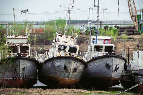 Free Three abandoned rusty boats docked on a riverbank, showcasing decay and nature's reclaim. Stock Photo