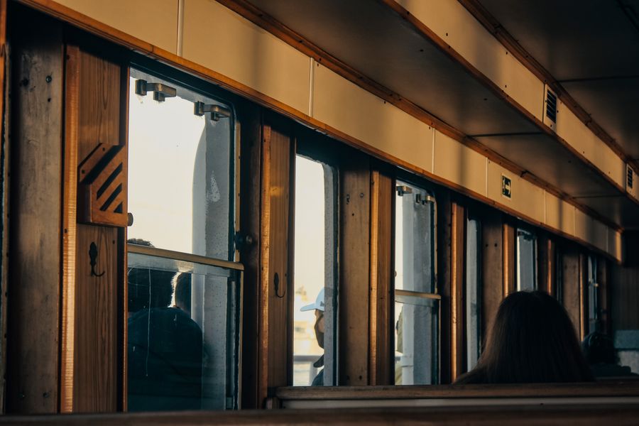A quiet train compartment with passengers observing the view outside through large windows.