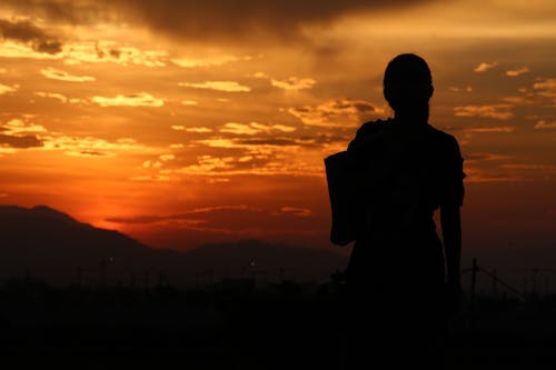 Silhouette of Person Standing on the Mountain during Sunset