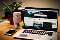 整洁的办公桌上放着一台笔记本电脑和一部智能手机，屏幕上显示着库存照片网站