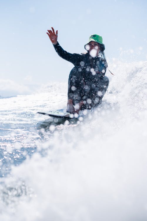 A Woman Wearing a Green Bucket Hat Riding the Waves