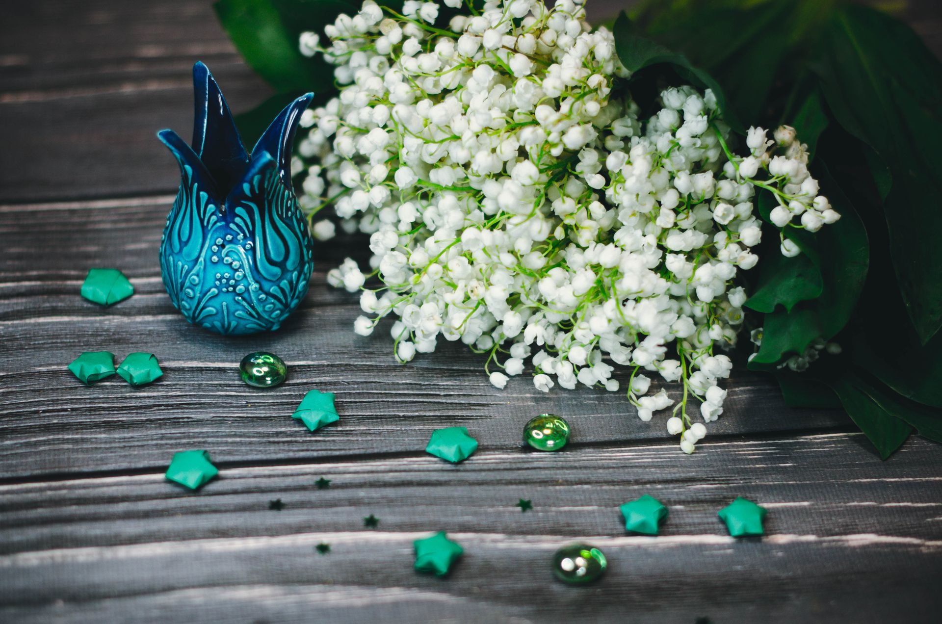 Elegant arrangement of lily of the valley on a wooden surface with turquoise decor, invoking serenity.