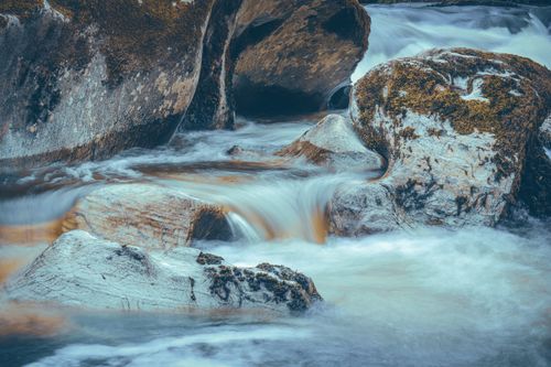 Free Serene creek cascading over moss-covered boulders in a peaceful Welsh landscape. Stock Photo
