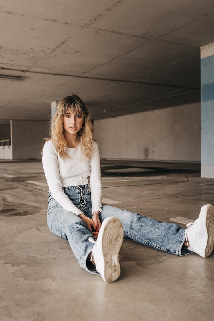 Female Sitting On Asphalt In Indoor Parking