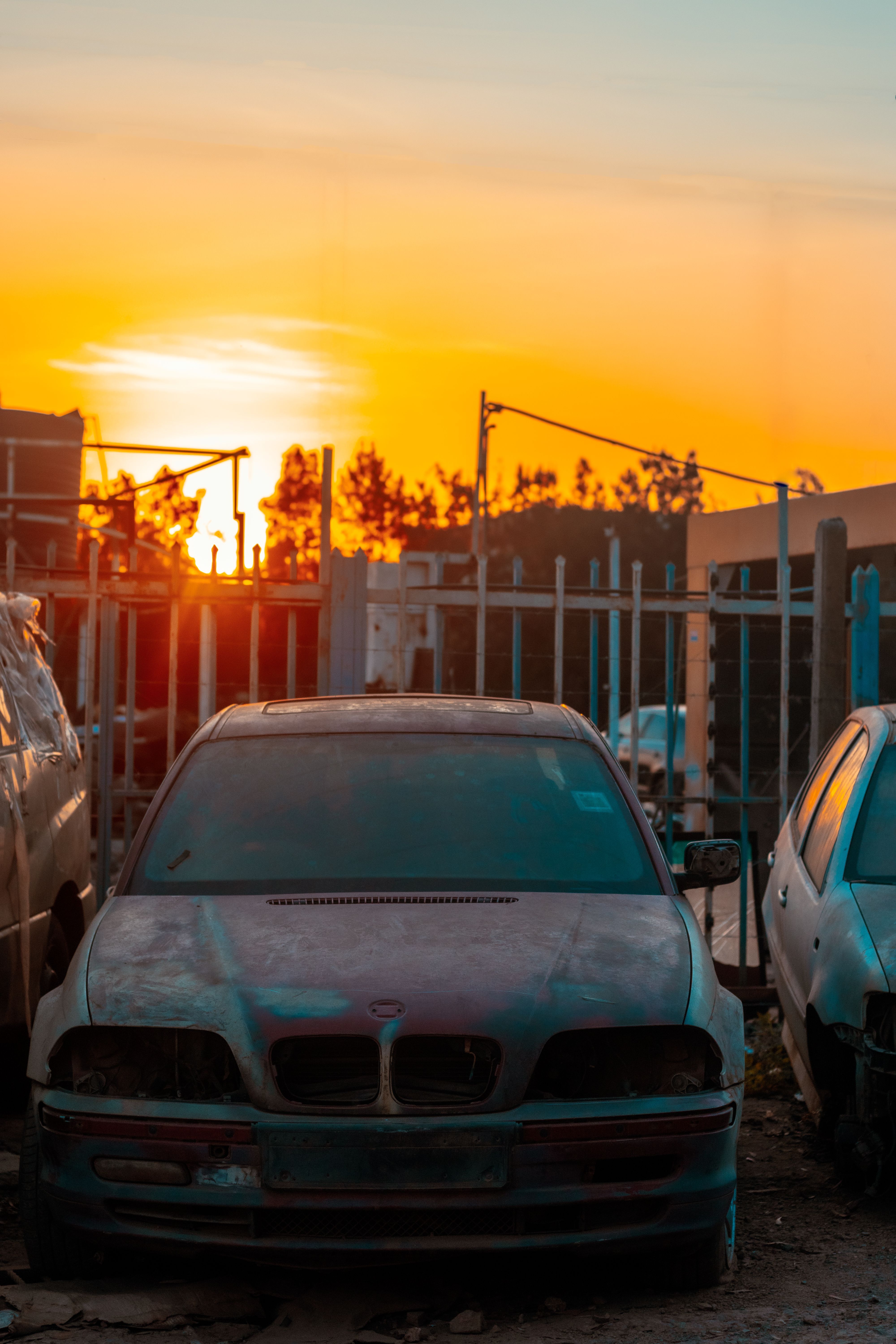 Rusty abandoned car in a Nairobi scrapyard during sunset, highlighting decay and neglect.