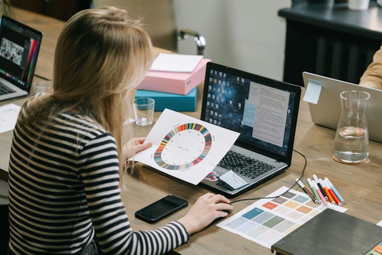 Woman Looking At A Color Wheel While Using A Laptop