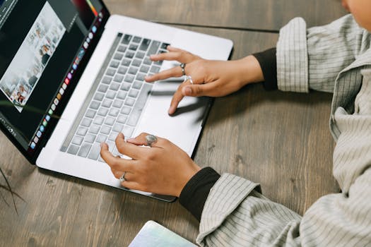 Close-up of hands typing on a laptop in a cozy, indoor setting showcasing creative digital work.