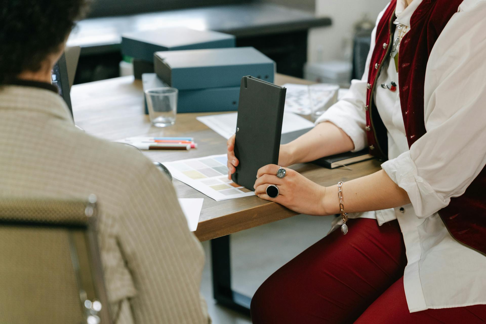 Business team engaged in a meeting at an office table, reviewing documents and color samples.