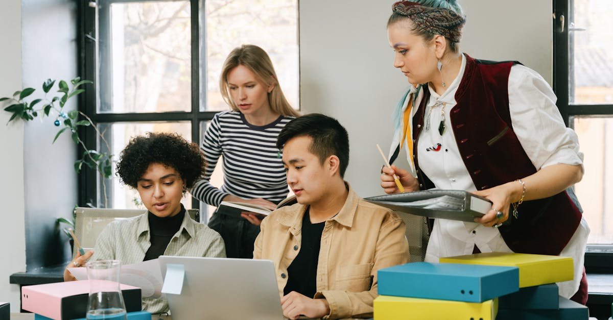 A diverse team in a meeting, one person speaking confidently with a laptop open showing a calendar