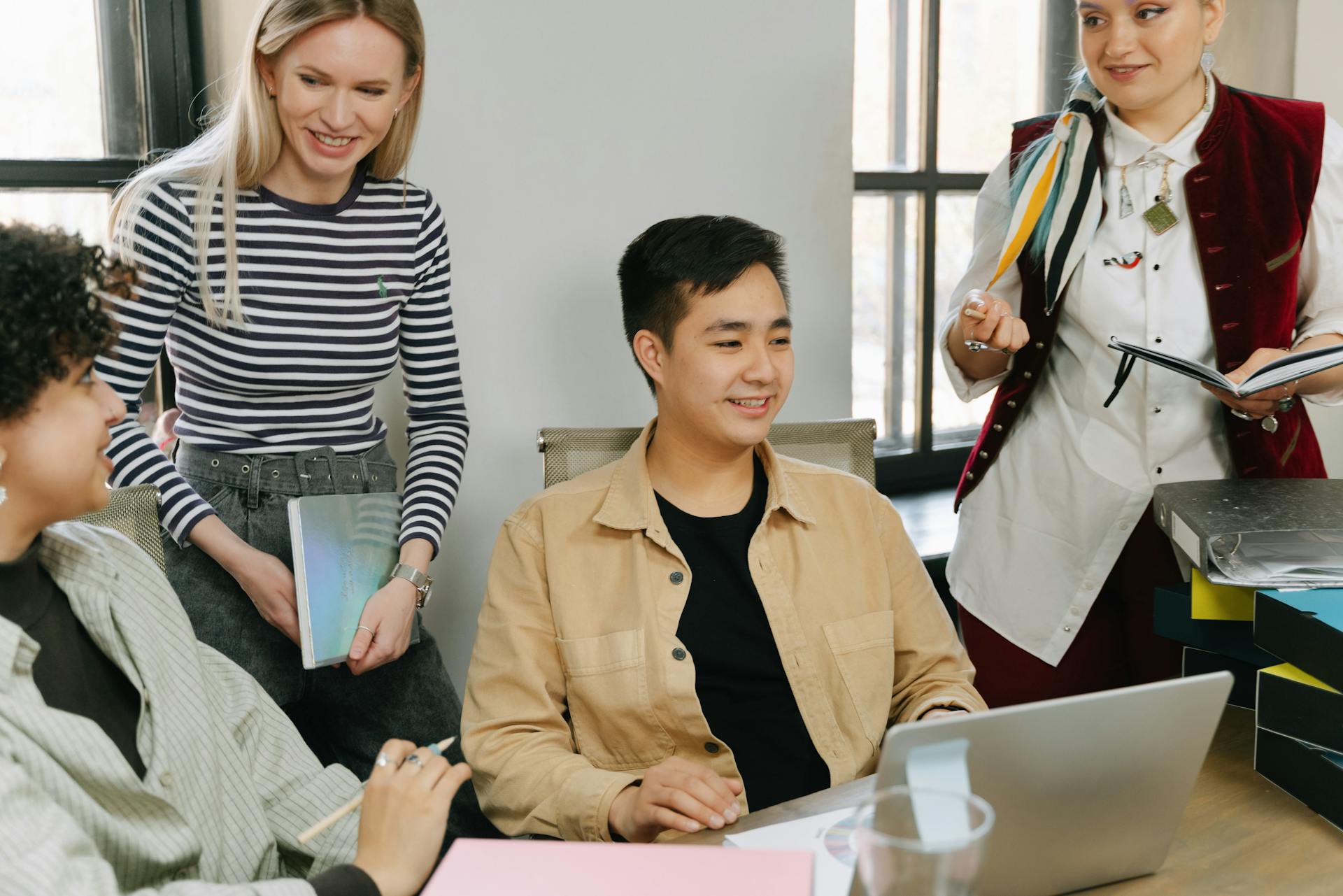 A diverse group of young professionals collaborating in a modern office setting, engaging in teamwork and discussion.