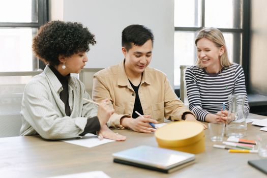 Three colleagues engage in a productive team meeting in a well-lit office space, fostering teamwork and discussion.