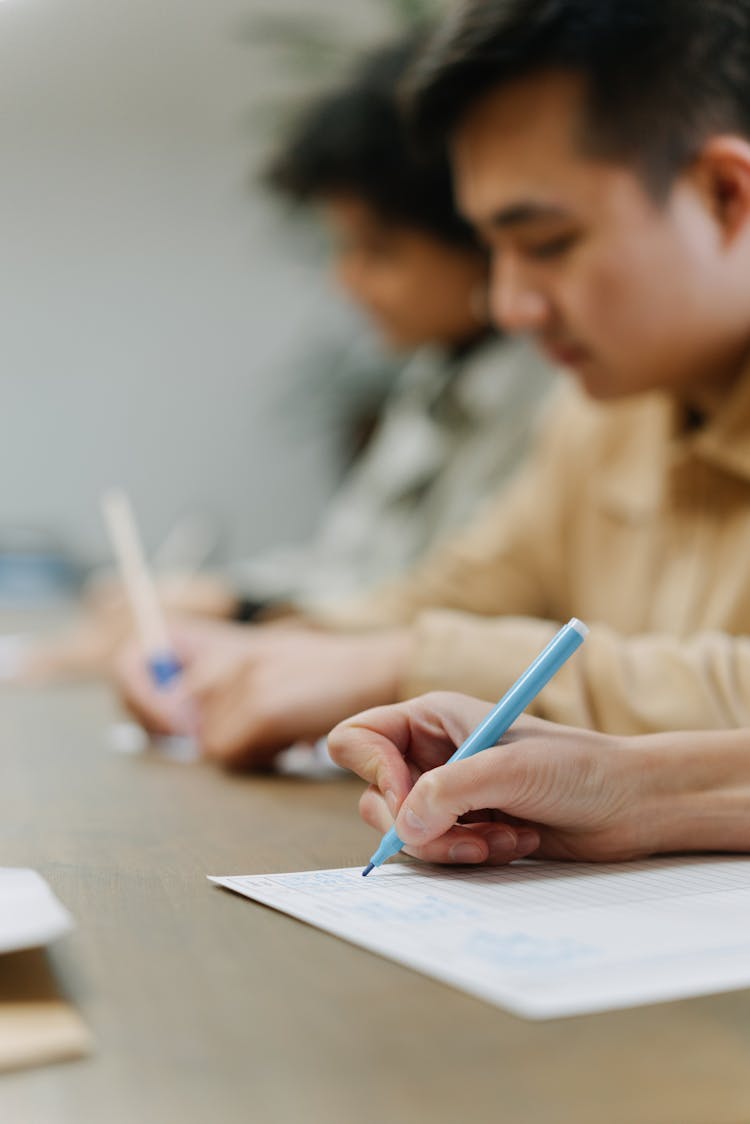 A Person Writing On Paper