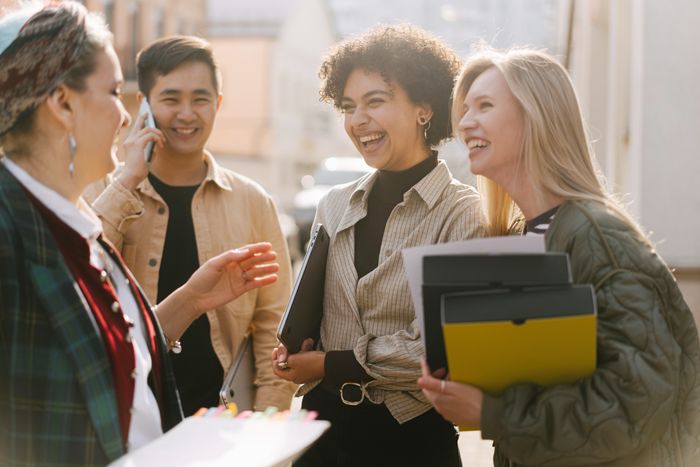 Colleagues laughing around a desk — photo by Ivan S on Pexels