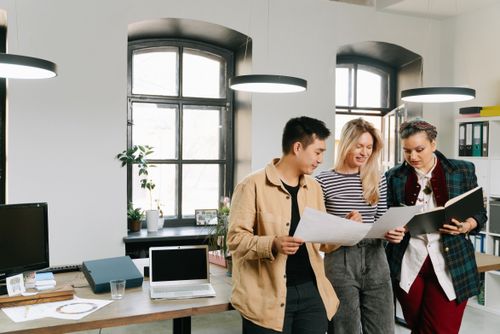 Free Three diverse colleagues engage in a strategy meeting in a well-lit modern office. Stock Photo