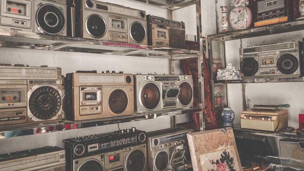 A collection of classic vintage boomboxes displayed on shelves indoors, evoking nostalgia.