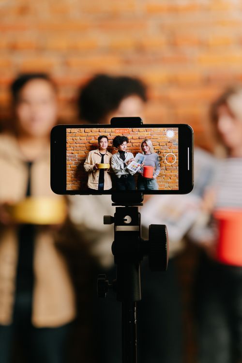 Mistä lähteä liikkeelle yrityksen oman audiosarjan kanssa? podcastin tekemisen vaiheet Mistä lähteä liikkeelle yrityksen oman audiosarjan kanssa? podcastin tekemisen vaiheet – Diverse group of friends filming video with smartphone