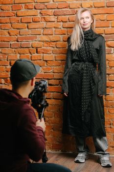 Model poses in a stylish black dress during a studio photo shoot.