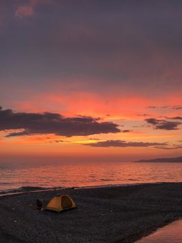 A picturesque beach sunset with a tent on the shore, creating a serene camping vibe.
