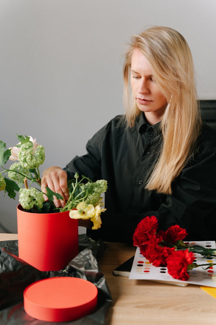 A Woman In Black Long Sleeves Arranging Flowers